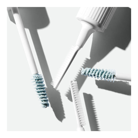 A close-up reveals RevitaLash Lash and Brow Masque on three white mascara wands and a comb-like tool over a light surface. The nutrient-rich blue mascaras cast diagonal shadows, adding depth while enhancing compromised lashes and brows.