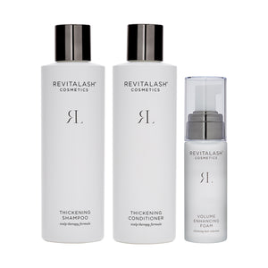 Three sleek products from the RevitaLash Volumizing Hair Collection Bundle adorn the display: a shampoo, conditioner, and foam. Each features minimalist black text on pristine white surfaces, elegantly topped with black caps or pumps.