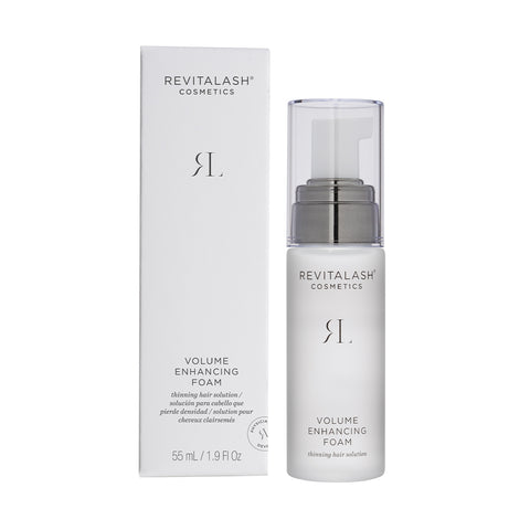 A white bottle of RevitaLash Volume Enhancing Foam for Hair (55mL) sits next to its box. Its minimalist design showcases grey and black text, a clear cap, and contains 55 ml (1.9 fl. oz.) of BioPeptin Complex for fuller-looking hair—ideal for thinning locks.