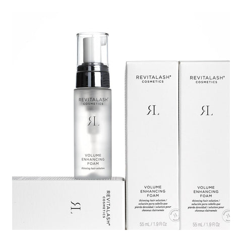 A 55mL transparent bottle of RevitaLash Volume Enhancing Foam for Hair, containing BioPeptin Complex for thinning hair, is shown with two white boxes featuring black text. The bottle has a sleek silver and black cap, while the boxes elegantly display product information in English.