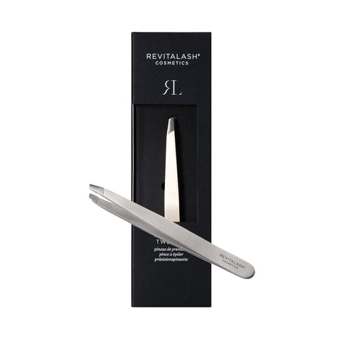 RevitaLash Precision Tweezers, crafted in a sleek silver design, are showcased on a black rectangular cardboard package reading REVITALASH COSMETICS TWEEZER. Positioned diagonally, they exude elegance and minimalism.